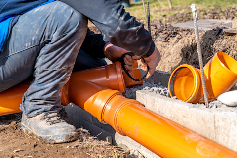 A technician installing a drainage system in a yard, with trenches being dug and pipes being laid out for proper water flow management.
