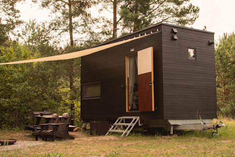 A small black modular house on wheels