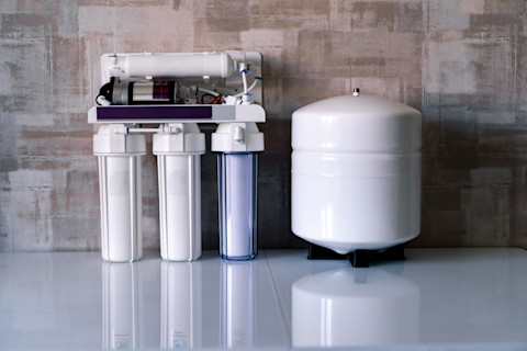 A reverse osmosis water filtration system installed under a kitchen sink, featuring multiple filters and a faucet for purified water.