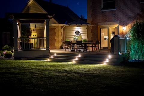 Illuminated backyard deck with table and chairs at night