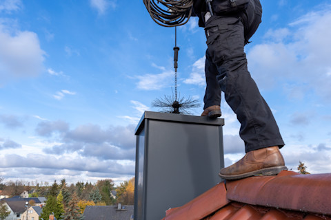 A handyman is sweeping a chimney