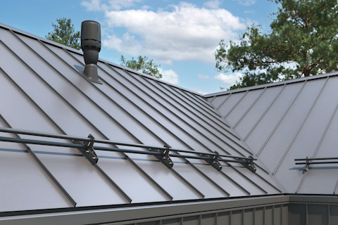 Close-up of a house retro roof panel with standing seam and fasteners and a chimney. The panel is a classic style black metal panel with a rebate joint made from modern galvanized steel.