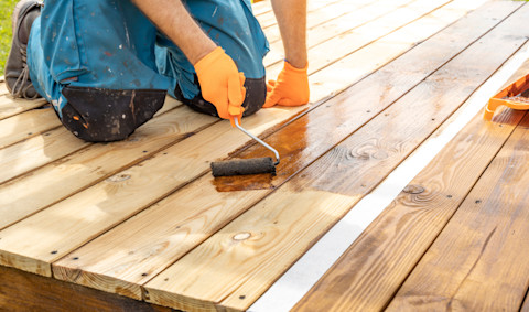 A man is varnishing a new wooden deck