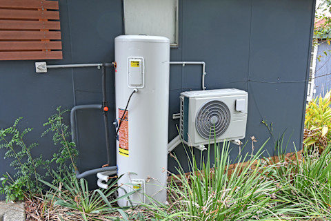 This image shows a heat pump hot water system on the exterior of a residential property.