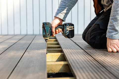 This image shows a close up of composite decking being installed. On top of the boards, there is a mallet and rubber fixings.