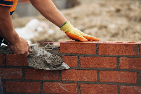 Using mortar and trowel to lay bricks