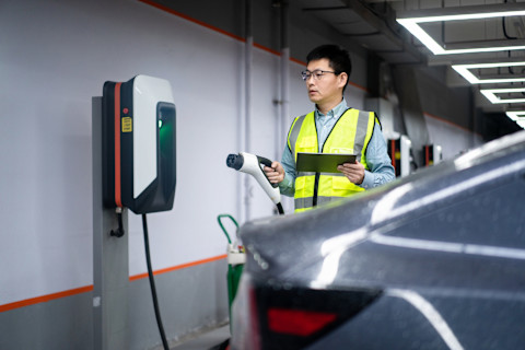 An engineer working with a digital tablet at a commercial EV charging installation site.
