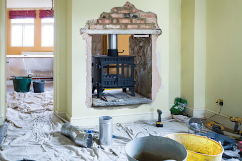 A fireplace installed in a dividing wall with a lot of clutter in the room.