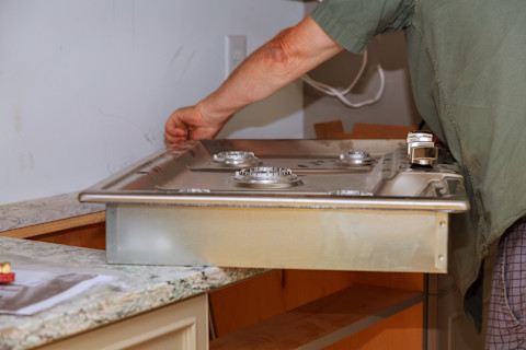 This image shows a gas stove being installed amongst kitchen worktops.
