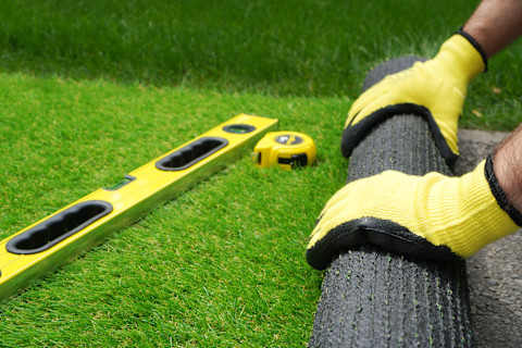 A tradesperson is laying artificial grass.