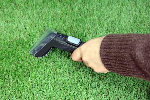 A person is cleaning artificial grass