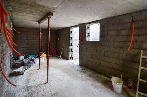 Construction of residential house cellar or basement with electric installations and freshly plastered walls.
