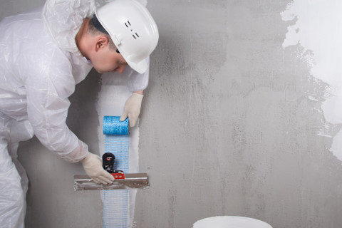 A man is replastering a wall