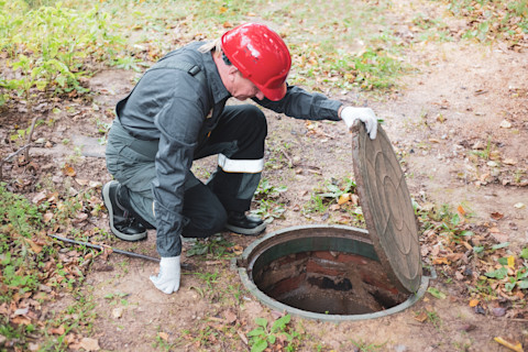 An image showing a partially excavated septic tank being repaired, with tools and equipment visible around the site, highlighting the process of fixing and maintaining a septic system