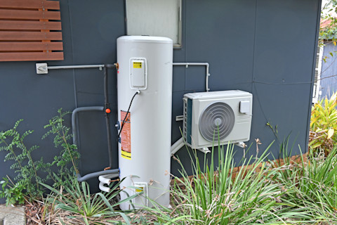 This image shows a heat pump hot water system on the exterior of a residential property.