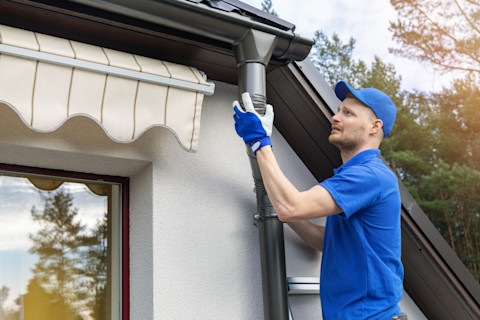 A tradesperson is repairing a broken gutter.