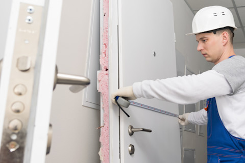 A tradesperson is measuring a door