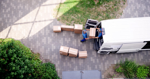 Two men are packing up a van with moving boxes.