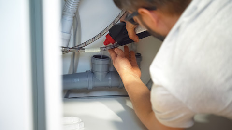 A plumber is unblocking a drain pipe.