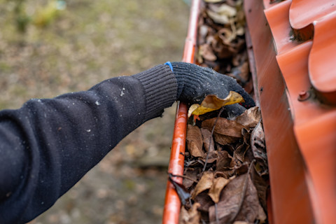 A tradesperson is clearing out a blocked gutter.