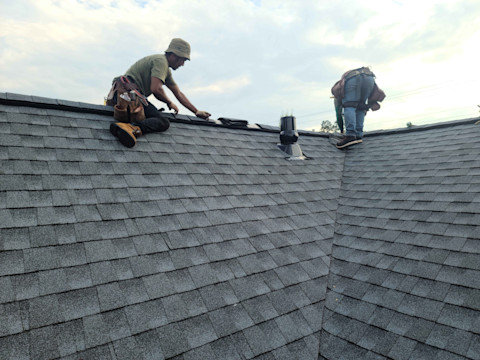 Roofers installing new tiles on a house roof