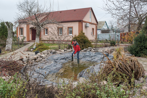 A workers draining the water and excavating the area to clear out the pond's debris and structure.