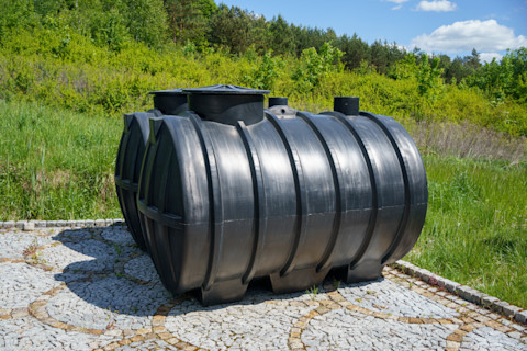Two plastic septic tanks designed for domestic sewage treatment, placed side by side on a construction site.