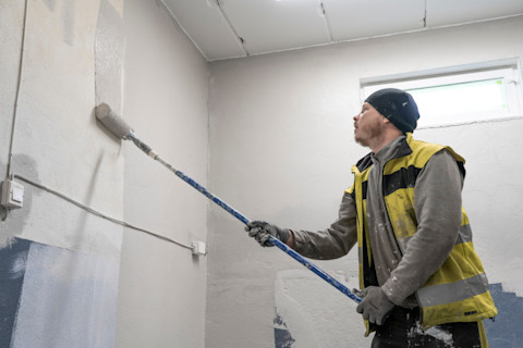 Empty residential garage with concrete floor and white painted walls, connected to a finished interior space, a potential area for conversion into a bedroom.