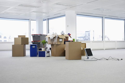 This image shows an office space that has been cleared out, there are some cardboard boxes ready to be packed and moved to another location.