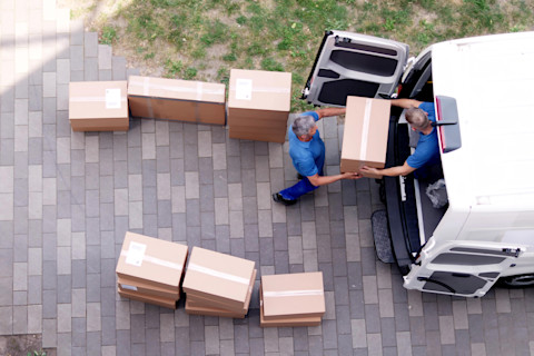 This image shows removal men putting cardboard boxes into a van, suggesting someone is moving house.