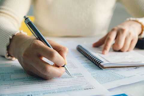 This image shows a woman filling in government forms with a pen.