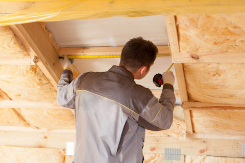 A tradesperson is boarding a loft including insulation.
