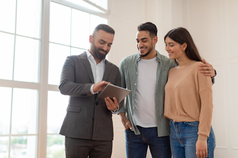 A builder dressed in black suit showing insurance documents to a couple.