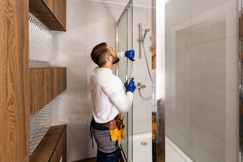 A bathroom fitter is renovating a new bathroom and fitting the shower.