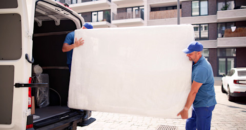 Two men loading a matrass in a van.